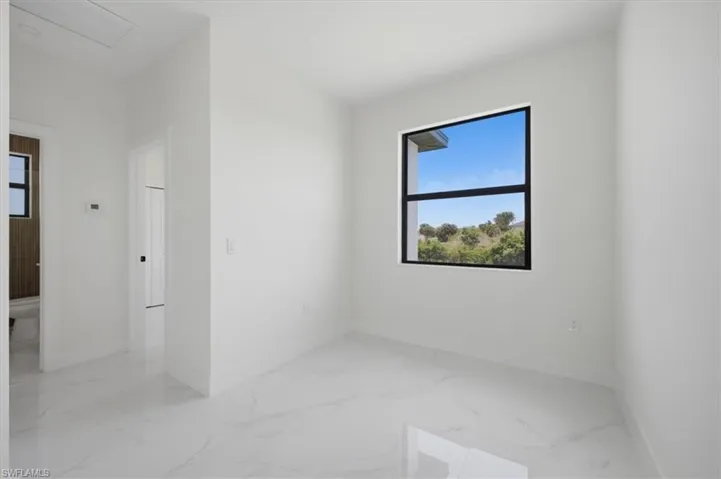 Bright room featuring a large black-framed window, white walls, and white-finish flooring