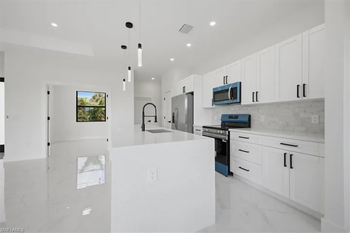 Sleek kitchen featuring white shaker cabinetry with matte black hardware, a light-toned countertop, and a coordinating subway tile backsplash