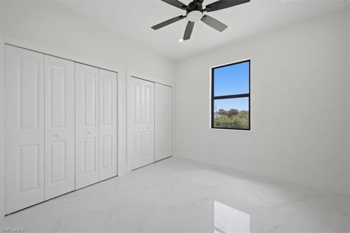 Bright room featuring bifold closet doors, a black-framed window, and a ceiling fan