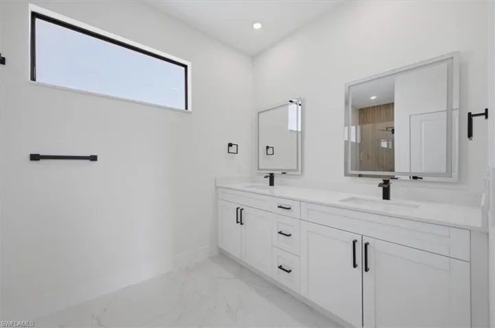 Dual vanity featuring white shaker cabinetry, quartz countertops, and matte black hardware