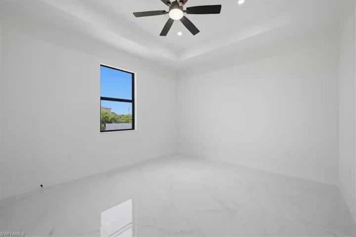 Bright interior space featuring a tray ceiling with recessed lighting and a ceiling fan
