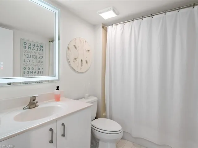 Bathroom featuring a single vanity with a laminate countertop, undermount sink, and brushed nickel faucet