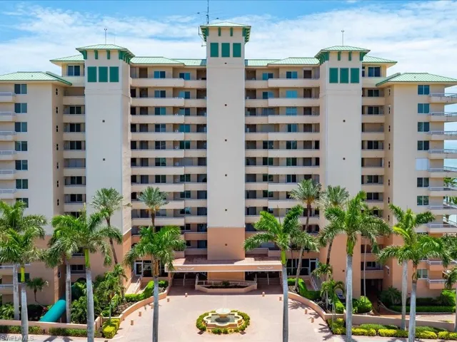 Multi-story condominium building featuring numerous private balconies and a light-toned exterior