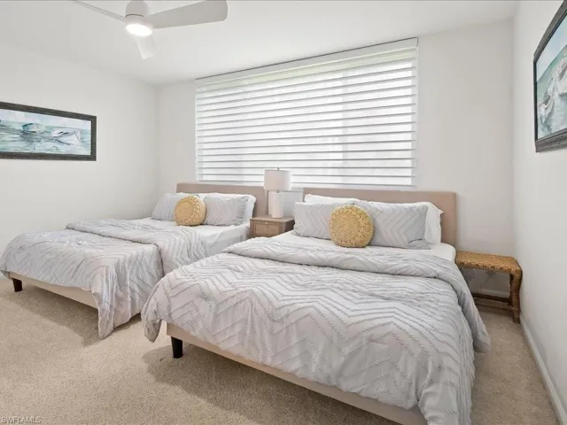Bedroom featuring neutral carpet flooring, a ceiling fan with integrated lighting, and a large window with horizontal blinds