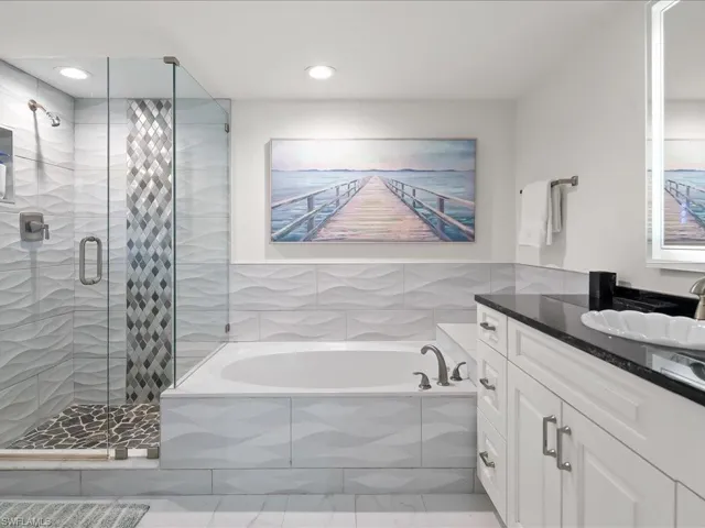 Bathroom featuring a glass-enclosed shower with pebble-tile flooring and a decorative tile accent strip