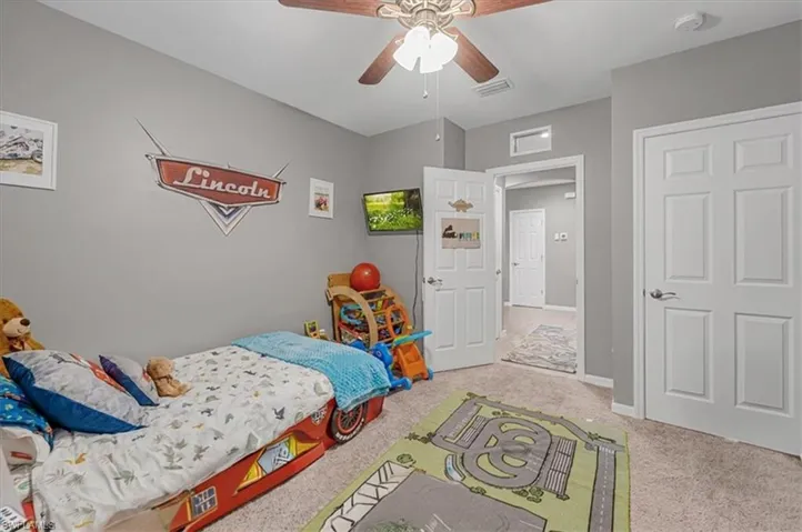 Carpeted room with light gray walls, a ceiling fan, and white paneled doors