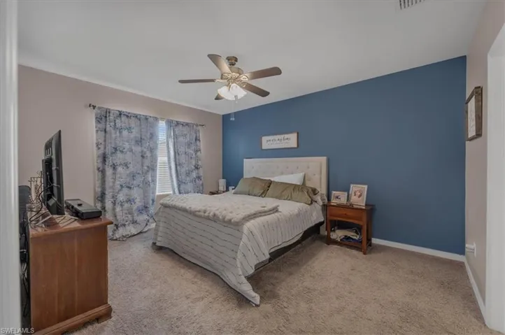 Bedroom featuring a prominent accent wall and window with blinds