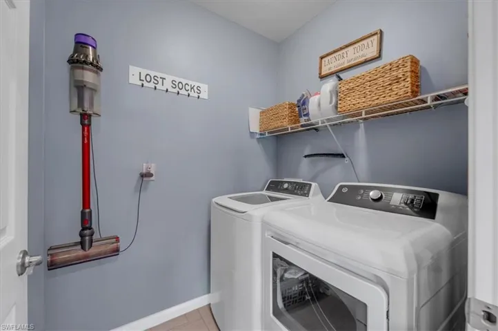 Dedicated laundry area featuring a washer and dryer, an overhead wire shelving unit, and light blue wall paint