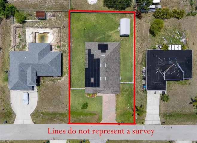 Aerial property view featuring a gabled roof, solar panel array, and a paved driveway