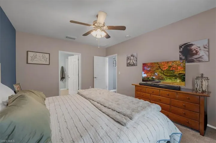 Spacious bedroom featuring a vaulted ceiling with a ceiling fan, a contrasting accent wall, and carpet flooring
