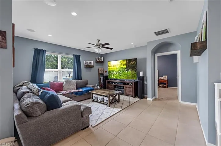 Spacious living area featuring tile flooring, an arched doorway, and recessed lighting