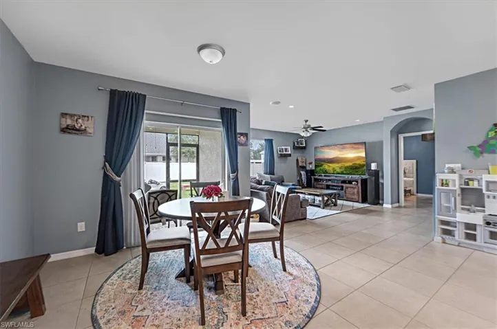 Open-concept living space featuring neutral tile flooring, light blue wall tones, and a sliding glass door providing natural light