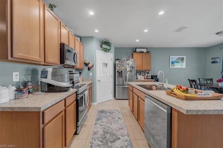 Spacious kitchen featuring light wood cabinetry, light-toned countertops, and stainless steel appliances including a refrigerator, dishwasher, oven, and microwave