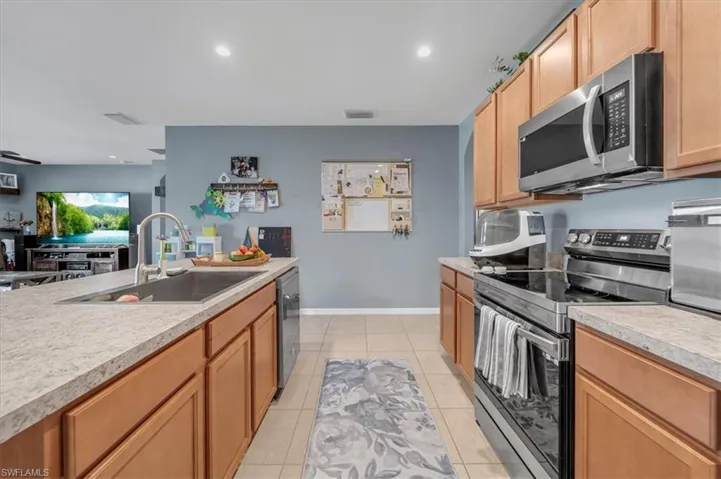Kitchen featuring wood cabinetry, stone-finish countertops, and stainless steel appliances including a built-in microwave and range