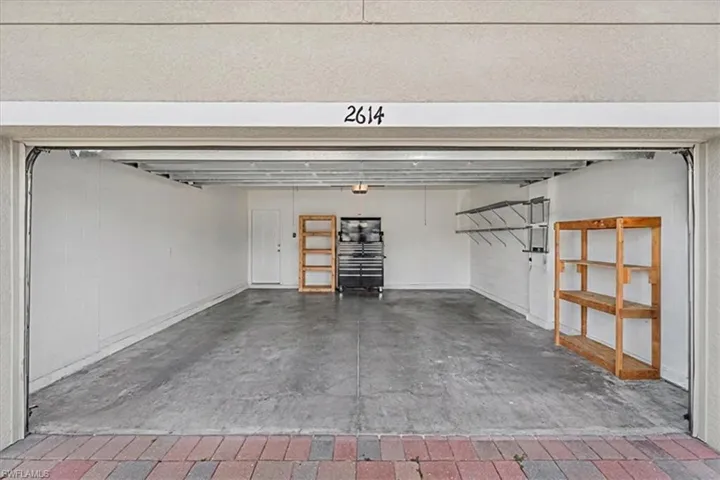 Spacious garage with a concrete floor, painted interior walls, overhead lighting, and a white interior door