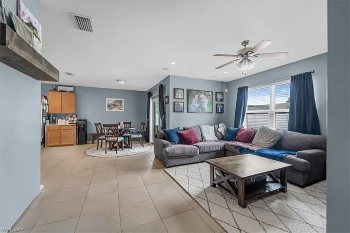 Open-concept living area featuring tile flooring throughout, a ceiling fan, and a built-in floating shelf