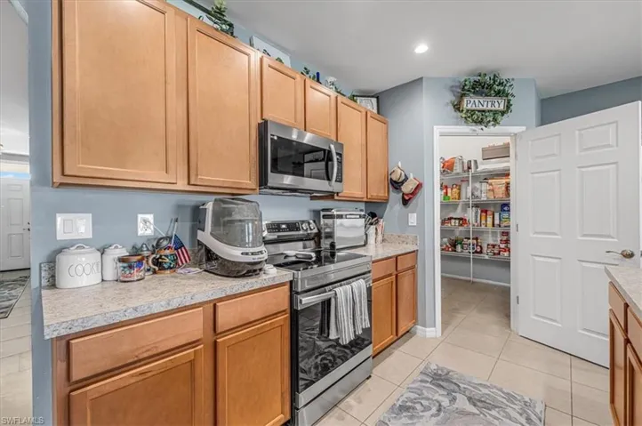 Kitchen featuring light wood cabinetry, light-toned countertops, and a full-size pantry with wire shelving