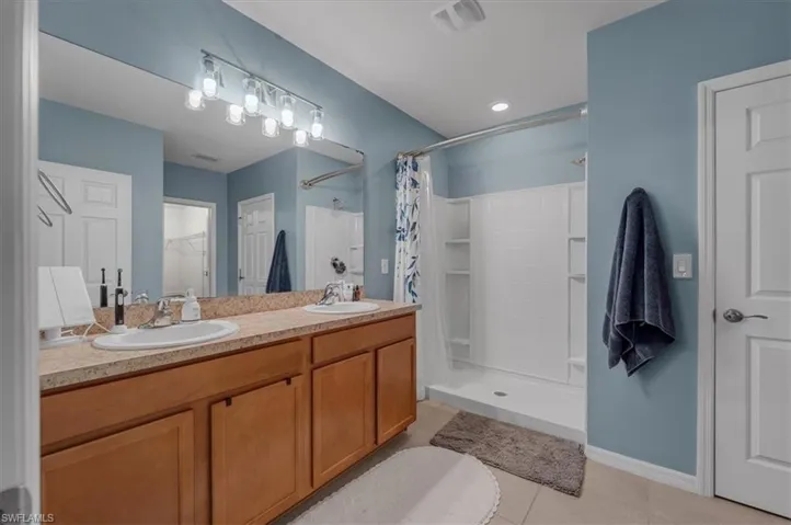 Bathroom featuring a dual vanity with undermount sinks, wood-finish cabinetry, and a light-toned countertop