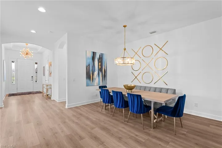Dining area with baseboards, a notable chandelier, wood finished floors, and recessed lighting