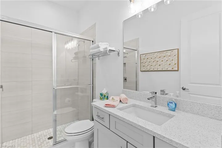 Bathroom featuring toilet, vanity, and a shower stall