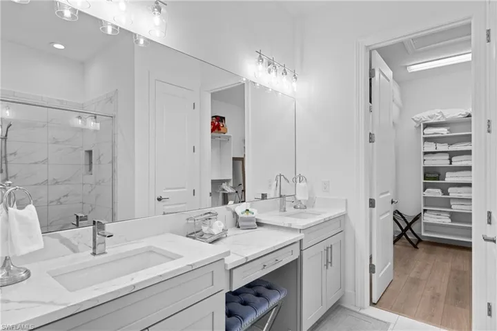 Full bath with a stall shower, a spacious closet, wood finished floors, and vanity