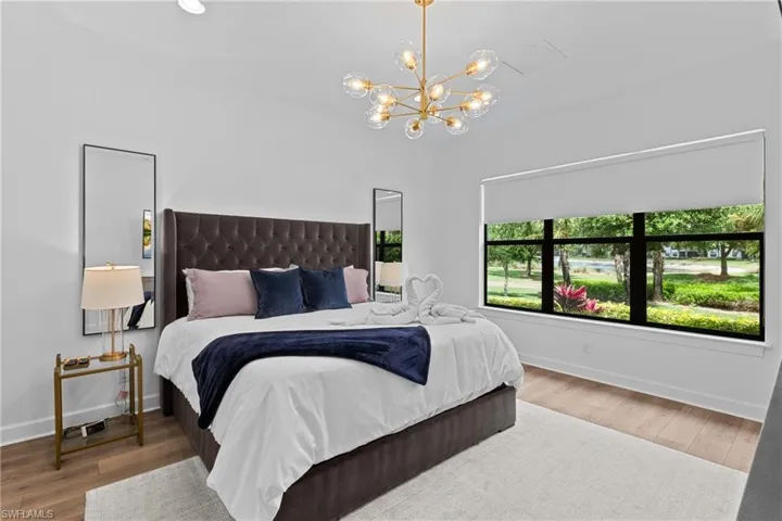 Bedroom with baseboards, a chandelier, and wood finished floors