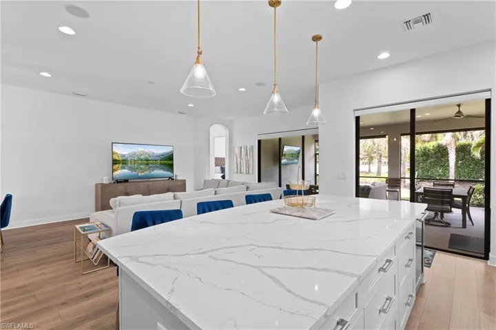 Kitchen with arched walkways, white cabinetry, light wood-style flooring, and recessed lighting