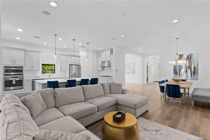 Living room featuring light wood finished floors, arched walkways, a chandelier, and recessed lighting