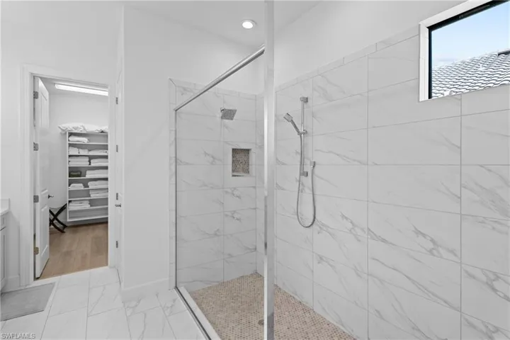 Bathroom with marble finish floor, recessed lighting, a walk in closet, and a walk in shower