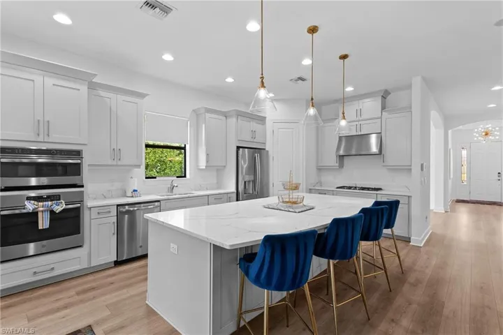 Kitchen featuring visible vents, a kitchen island, appliances with stainless steel finishes, under cabinet range hood, and a sink