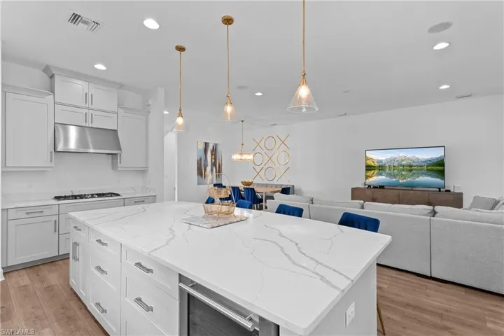 Kitchen with visible vents, wine cooler, recessed lighting, under cabinet range hood, and open floor plan