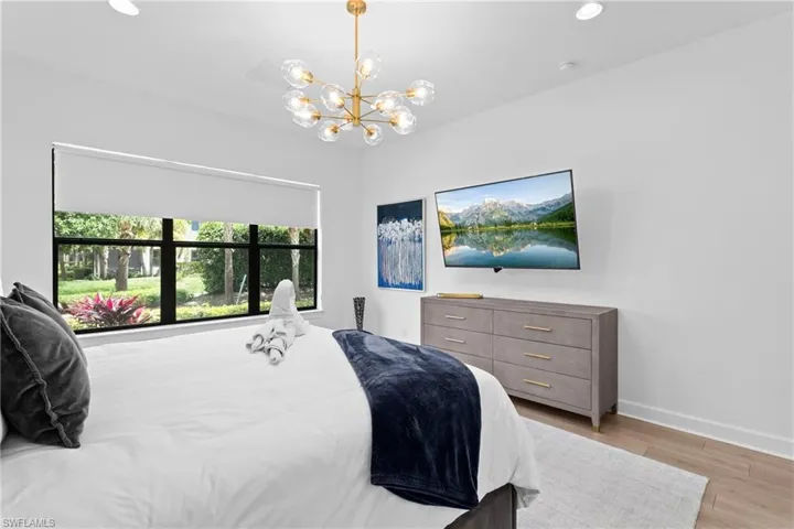 Bedroom featuring baseboards, light wood-style flooring, recessed lighting, and a notable chandelier