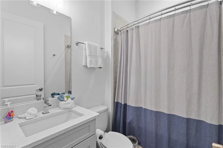 Bathroom with a shower with shower curtain, toilet, and vanity