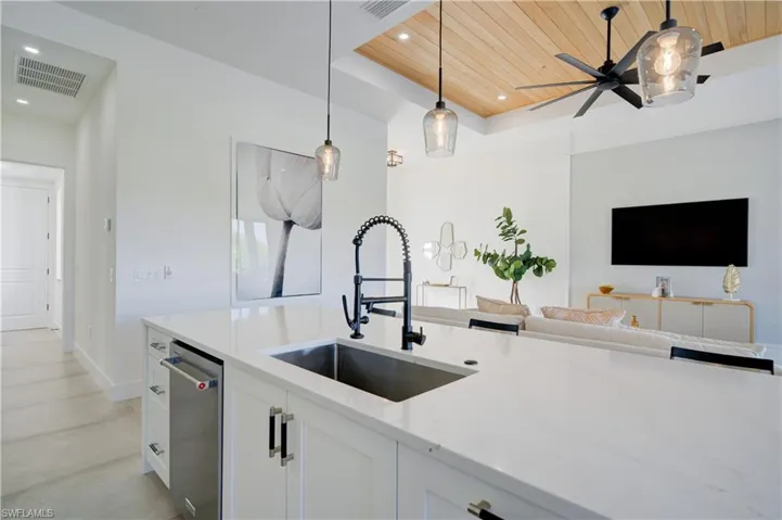 Kitchen with white cabinets, pendant lighting, wood ceiling, and sink