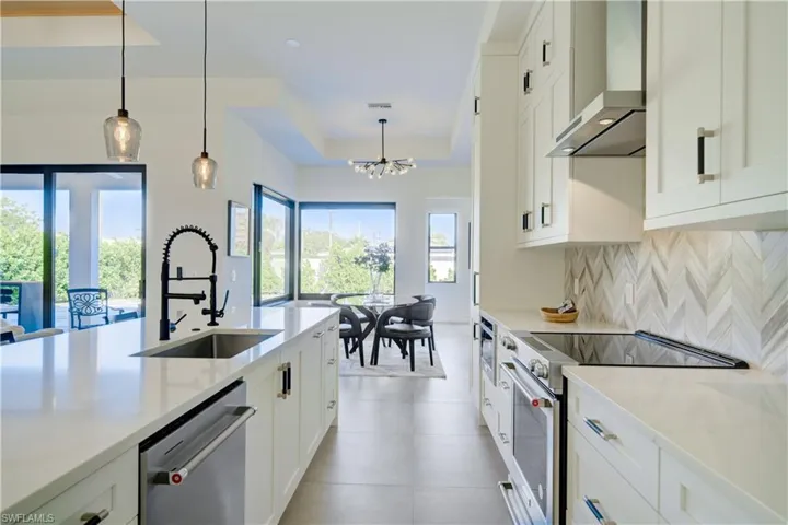 Kitchen with appliances with stainless steel finishes, white cabinetry, and wall chimney exhaust hood