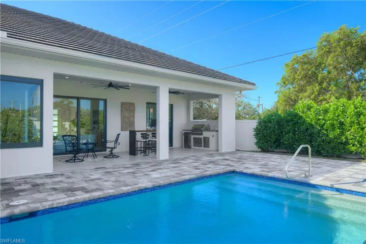 View of pool featuring area for grilling, ceiling fan, a bar, a patio, and a grill