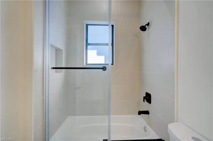 Bathroom featuring tiled shower / bath combo and toilet