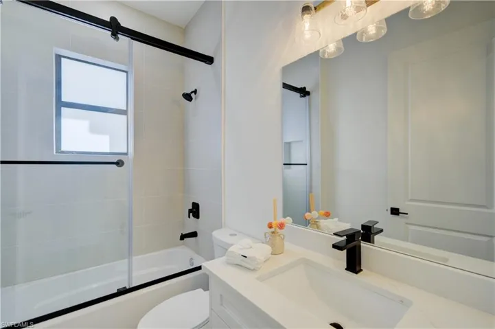 Full bathroom featuring vanity, enclosed tub / shower combo, and toilet