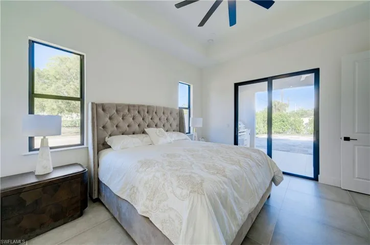 Bedroom featuring multiple windows, access to exterior, and ceiling fan