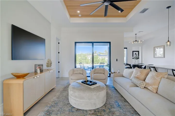 Living room featuring ceiling fan with notable chandelier, a tray ceiling, and wood ceiling