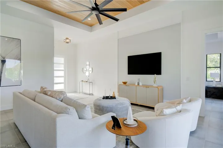Living room with a tray ceiling, ceiling fan, and wooden ceiling