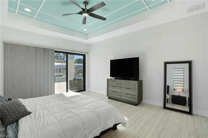 Bedroom with access to exterior, a raised ceiling, light wood-style floors, ceiling fan, and recessed lighting