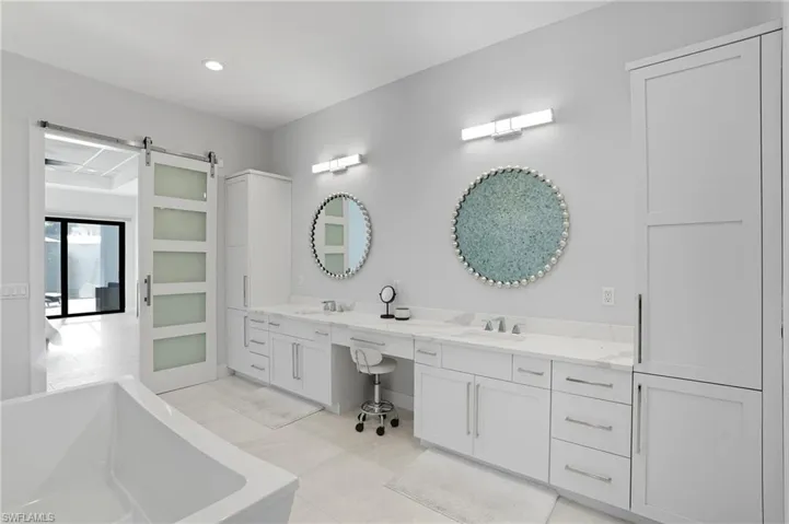 Bathroom with a freestanding bath, double vanity, recessed lighting, and light tile patterned flooring