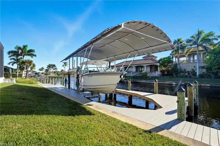 Dock area with boat lift, a lawn, and a water view