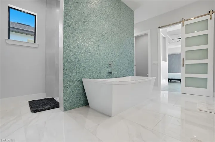 Ensuite bathroom featuring a freestanding bath and baseboards