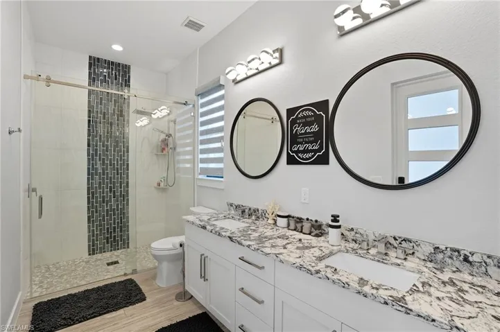 Full bath with a shower stall, double vanity, and recessed lighting