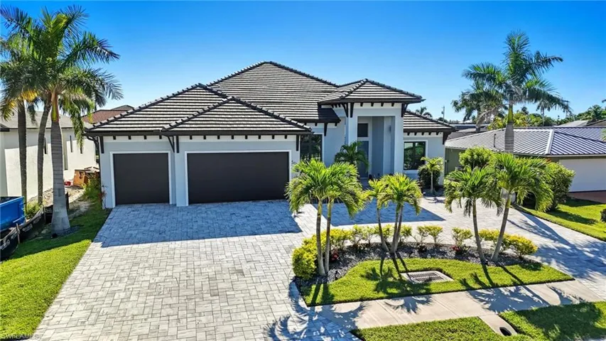View of front of house featuring decorative driveway, an attached garage, stucco siding, and a tile roof