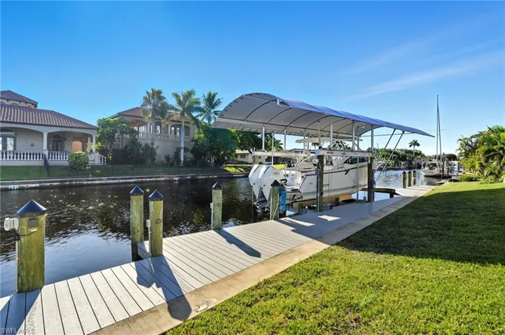 Dock area with a lawn, boat lift, and a water view