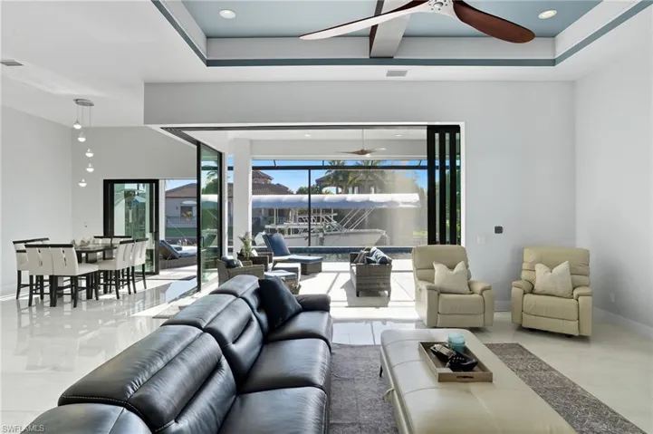Living room with recessed lighting, a ceiling fan, a raised ceiling, and light tile patterned flooring