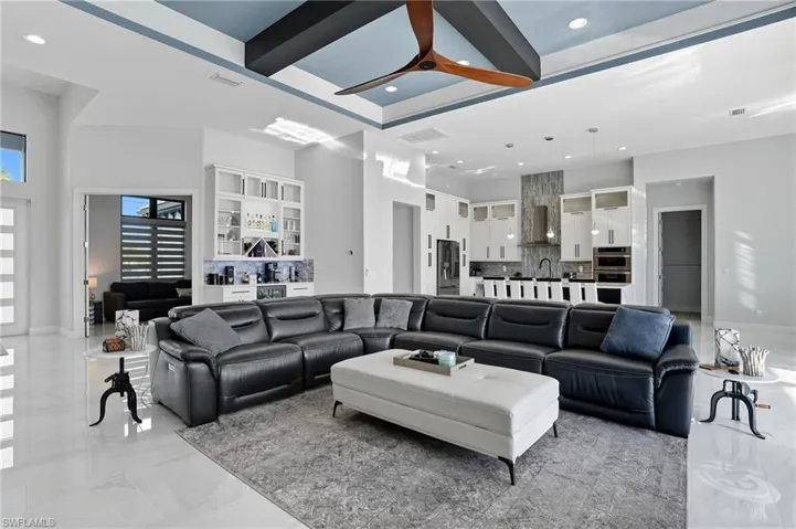 Living area featuring beam ceiling, coffered ceiling, recessed lighting, a towering ceiling, and ceiling fan
